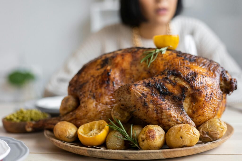 Palatable roasted turkey with potatoes and lemon on wooden round tray placed on table for celebrating Thanksgiving Day