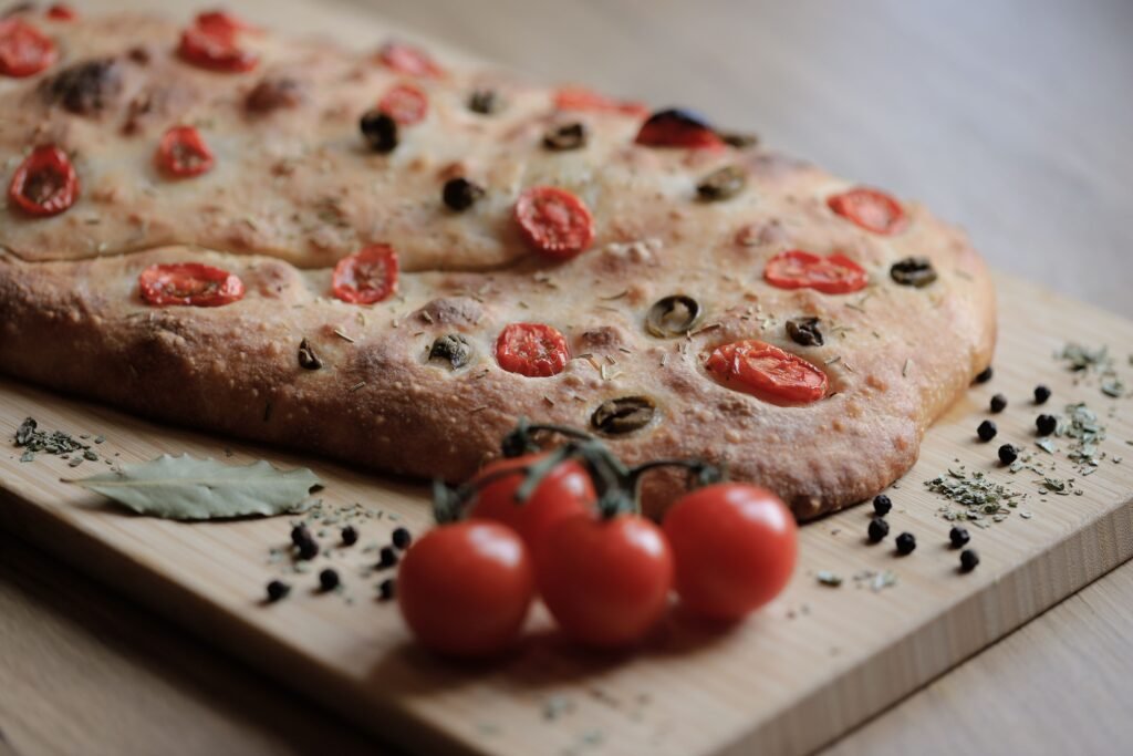 Delicious focaccia bread topped with cherry tomatoes and olives, perfect for home baking enthusiasts.